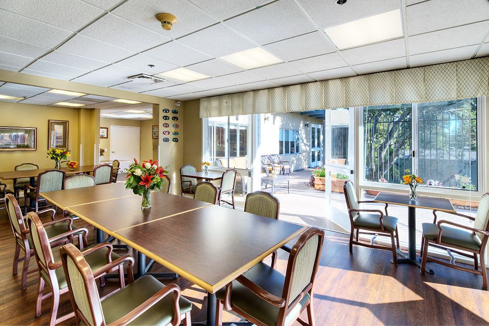 A well-lit conference room with a table and chairs, featuring a flower vase and large windows.