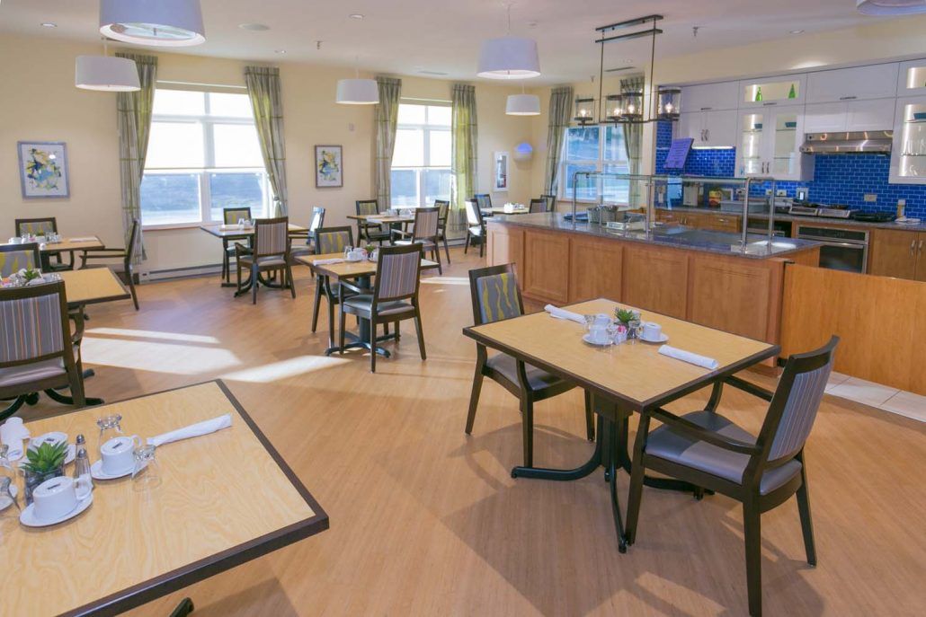 A well-lit restaurant dining area with neatly arranged tables and chairs on a wooden floor.