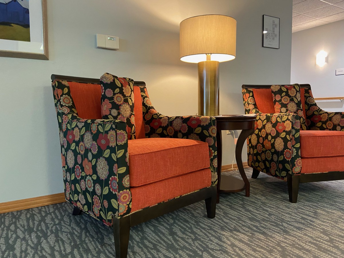 A cozy living room setup with two patterned armchairs and a side table topped with a lamp.