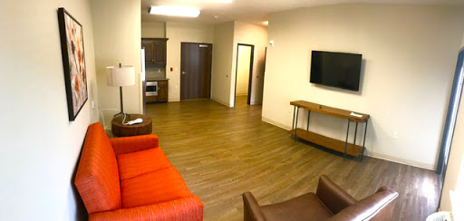 A spacious living area featuring modern furniture and a kitchenette.