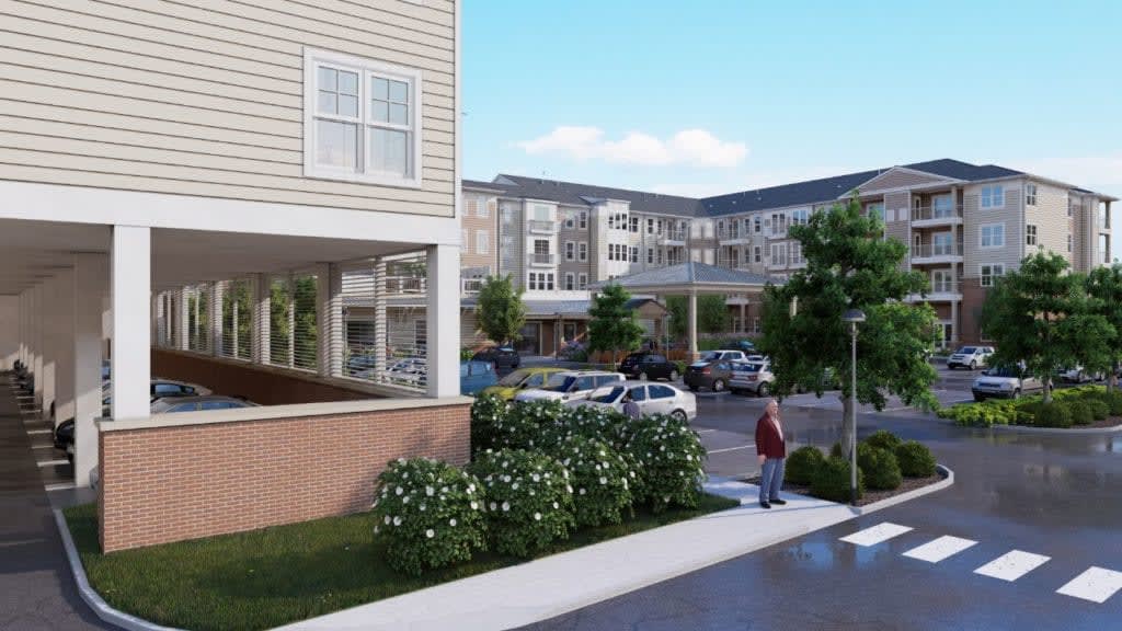 A residential apartment complex with a parking lot and landscaped surroundings.