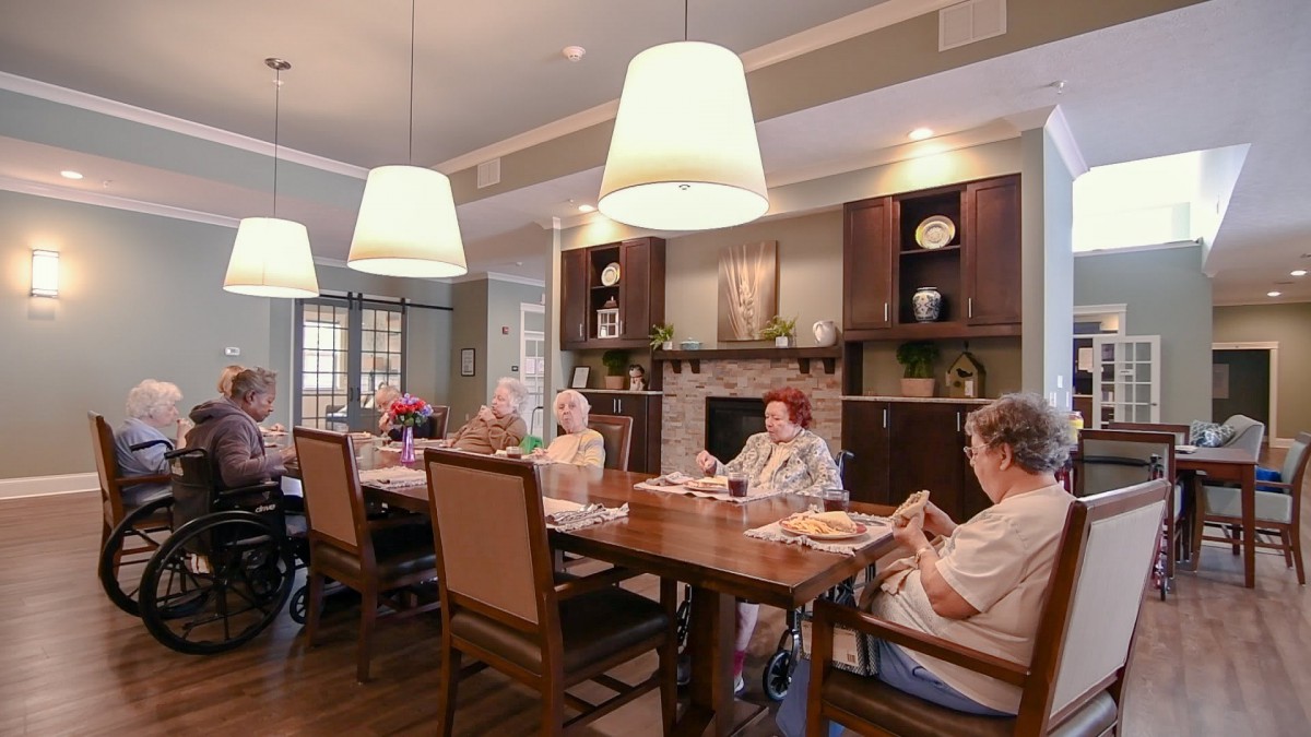 A group of seniors sitting around a dining table in a cozy, well-lit room.