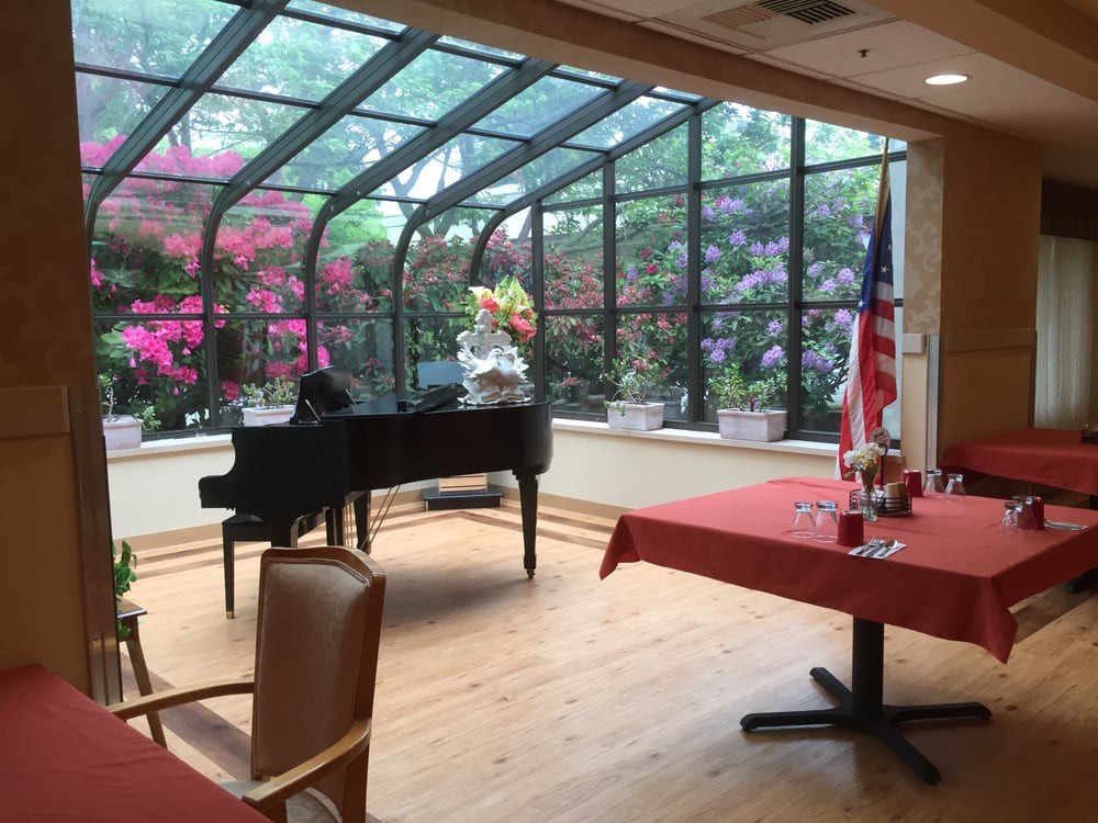 A cozy room featuring a grand piano and a garden view through large windows.