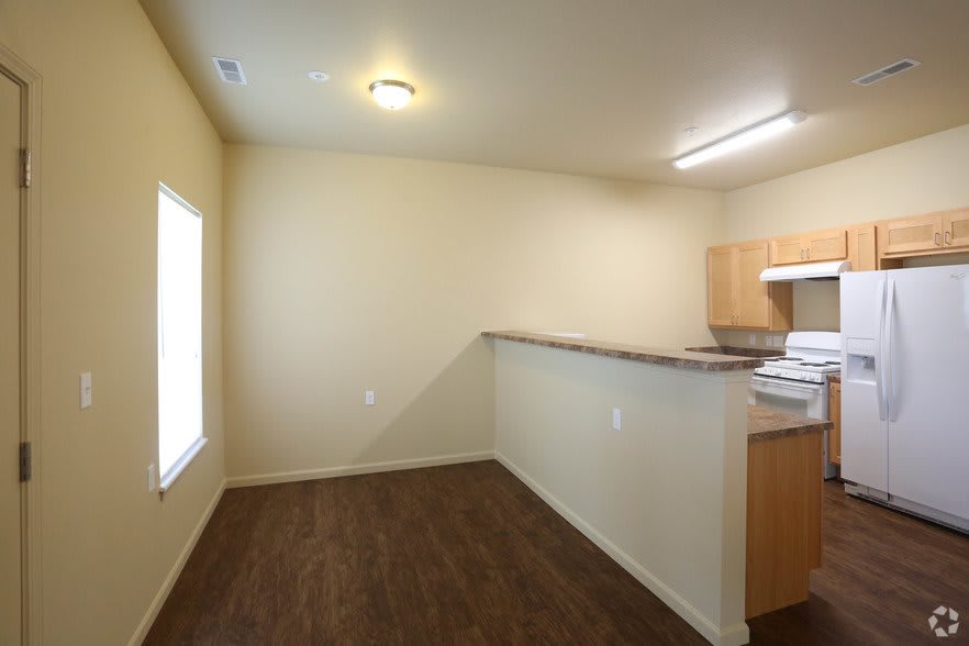 An empty kitchen and dining area with wood flooring and open layout.