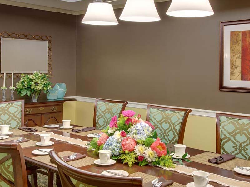 An elegantly set dining room with a floral centerpiece and warm lighting.