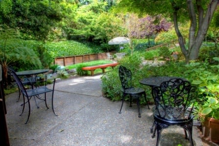 A tranquil garden patio with outdoor seating surrounded by lush greenery.