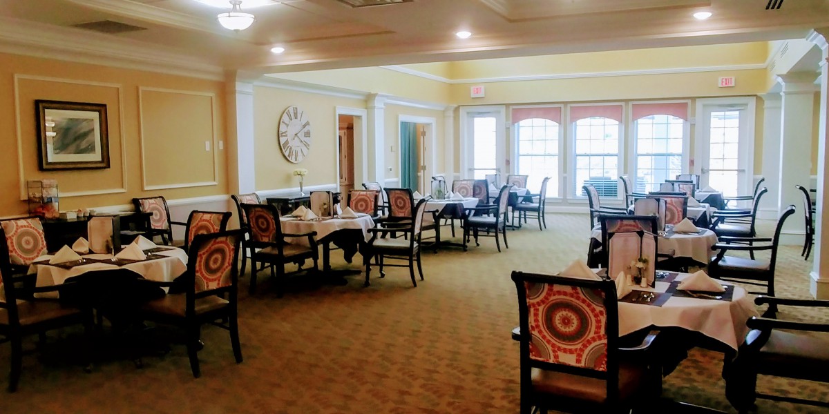 A well-lit dining room with neatly arranged tables and chairs.