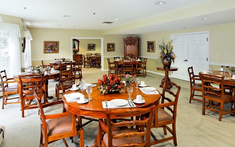 An elegantly set dining room with several tables and chairs, featuring stylish decor.