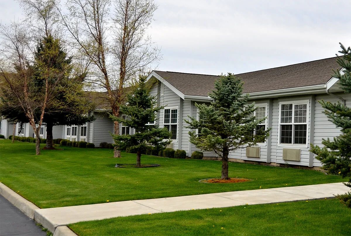 A suburban house with a well-maintained lawn, trees, and a pathway.