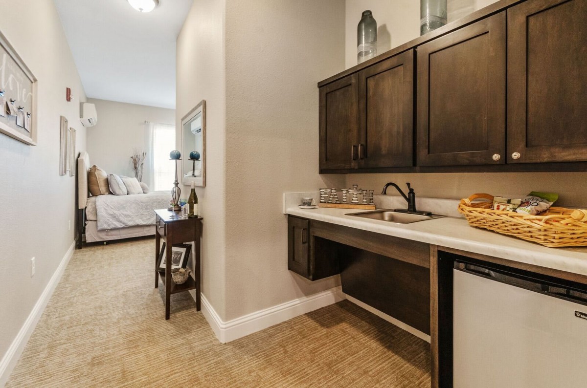 A cozy bedroom featuring an adjacent vanity area with a sink and cabinets.