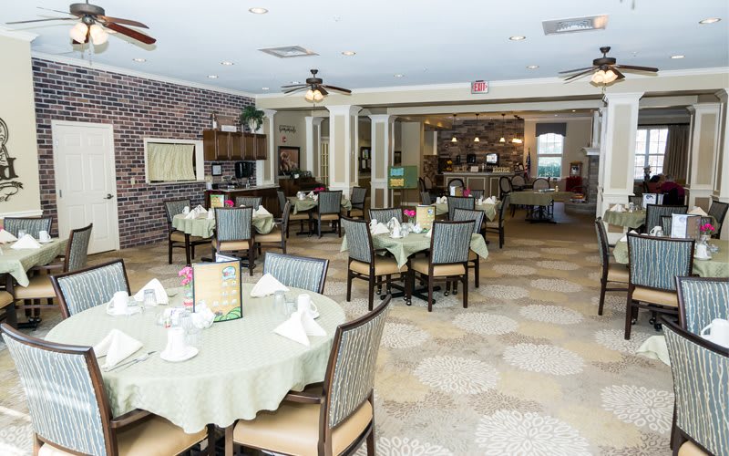 A spacious restaurant dining area with neatly arranged tables and chairs, featuring elegant place settings.