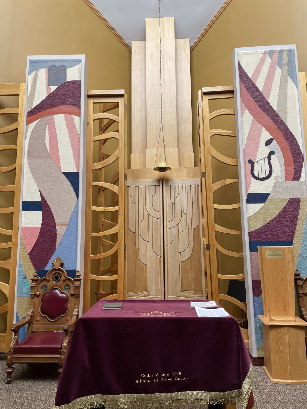Interior view of a synagogue altar with colorful banners and symbolic designs.