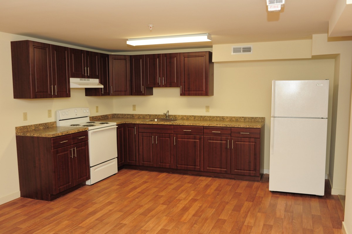 A modern kitchen with dark wood cabinets and hardwood flooring.