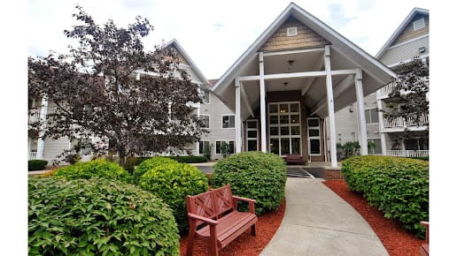 An inviting building entrance with benches and lush landscaping.