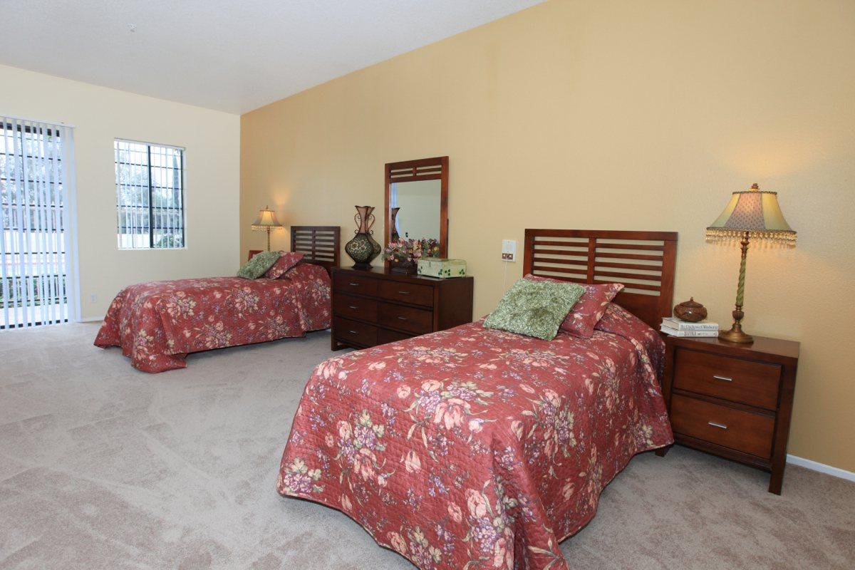 A cozy bedroom with two twin beds adorned with floral bedding and a wooden dresser with a mirror.