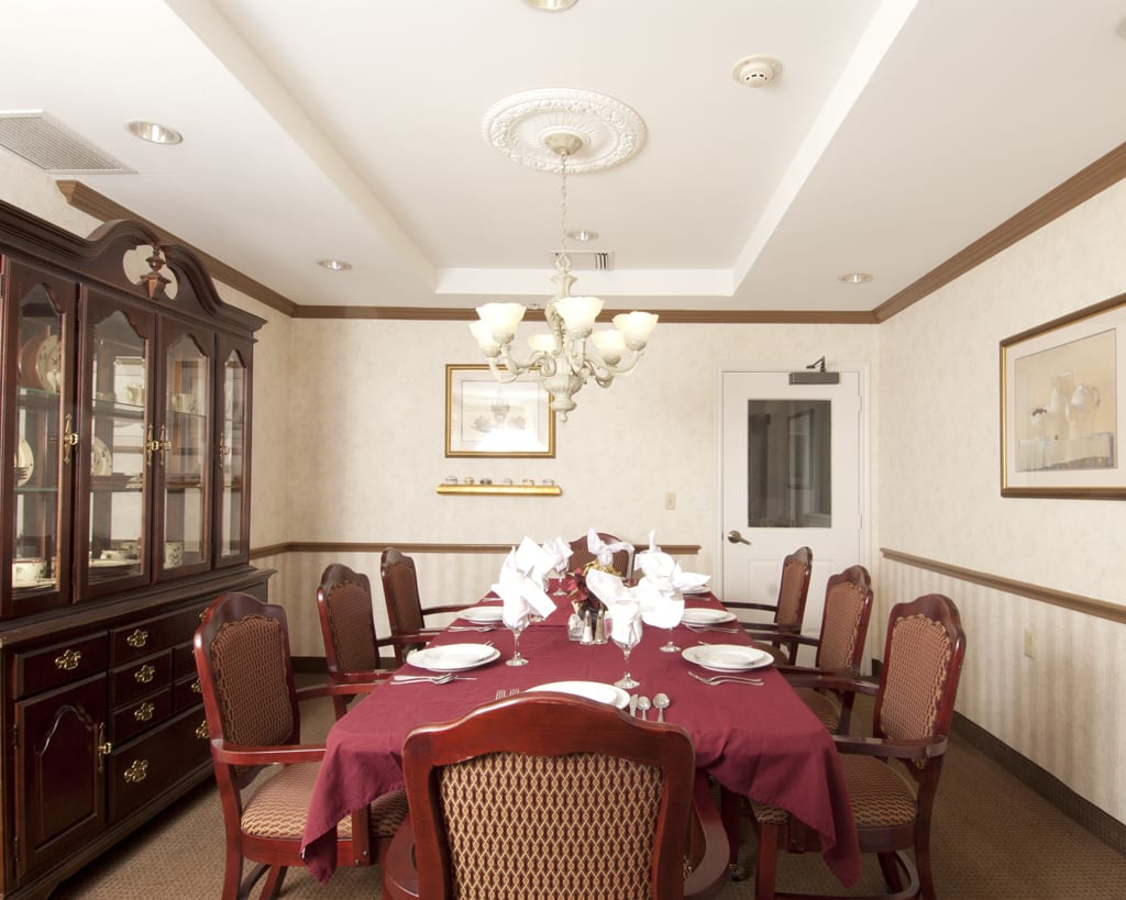 An elegant dining room with a chandelier hanging over a table set for dinner.