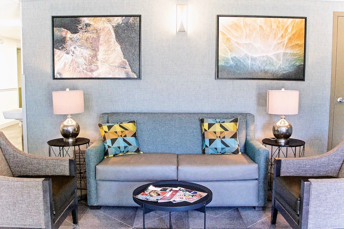 A stylish living room with a sofa, decorative cushions, and artwork on the walls.