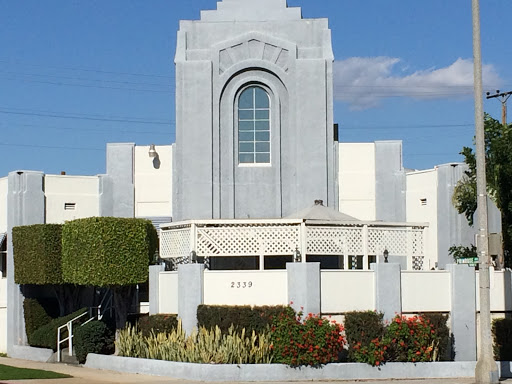 A striking modern building with a prominent arch window, surrounded by well-maintained landscaping under a clear blue sky.