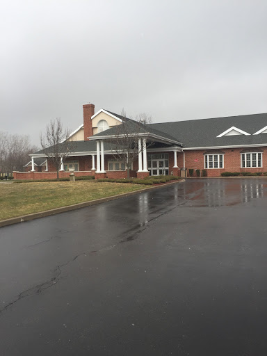 A residential building with a brick facade and a covered porch, set against an overcast sky.