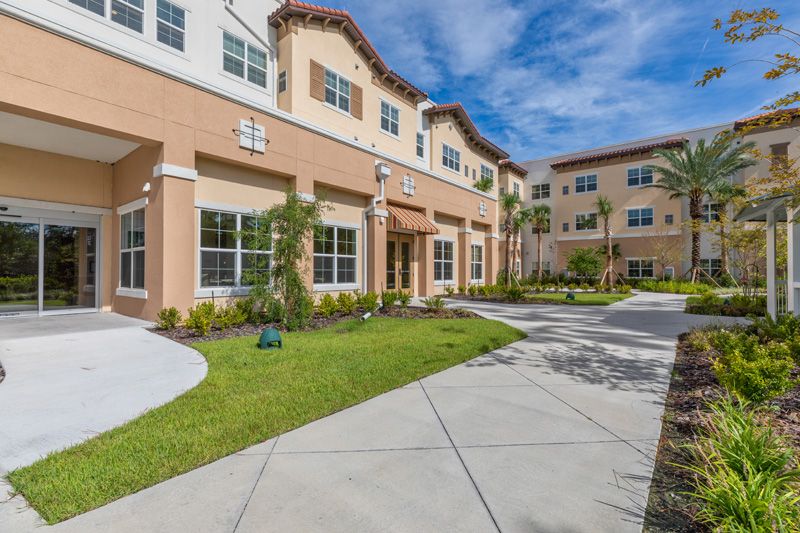 Modern apartment complex with well-maintained landscaping under a clear blue sky.
