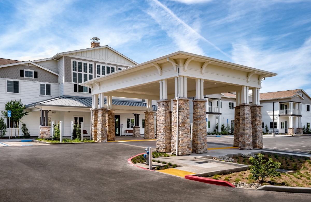A modern building entrance with stone columns and a covered driveway.