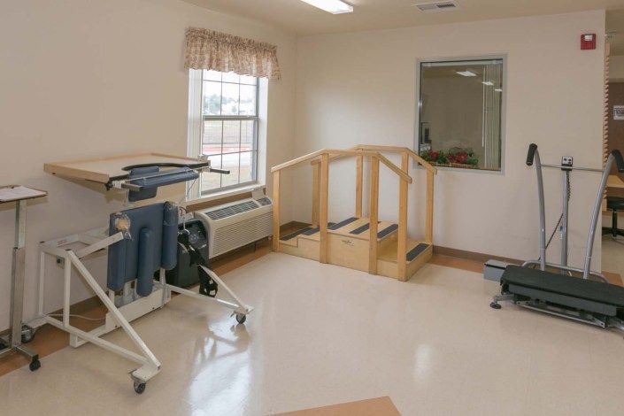 A rehabilitation room with physical therapy equipment including a set of parallel bars and support devices.
