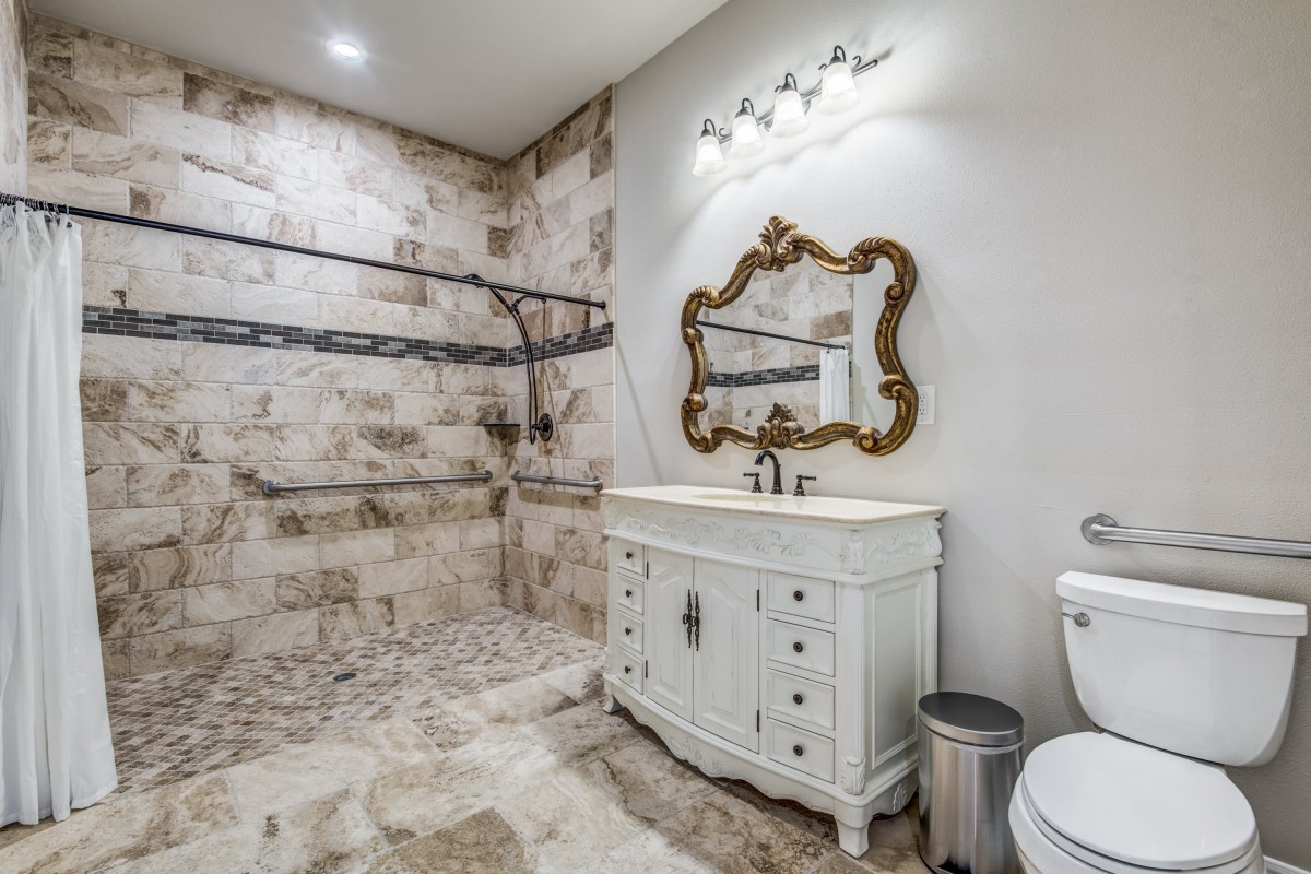 A rustic yet elegant bathroom featuring a large walk-in shower, ornate mirror, and vintage-style vanity.