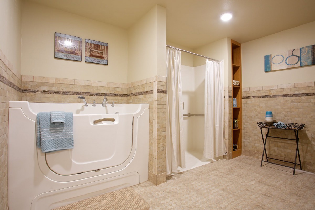 A modern, accessible bathroom featuring a walk-in tub and shower with beige tiling.