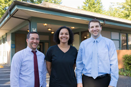 A cheerful group of three individuals posing together outside a building.