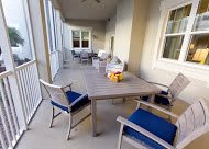 A spacious patio with a wooden table and blue-cushioned chairs.