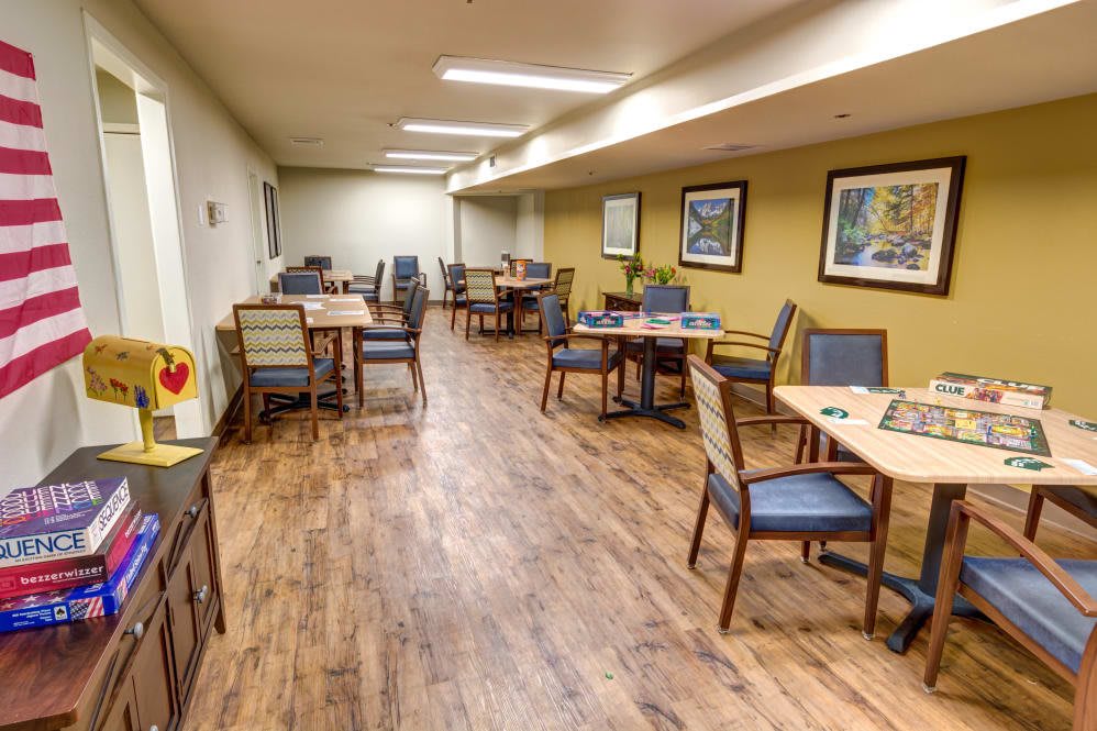 A neatly arranged dining area with tables and chairs, featuring hardwood floors and decorative artwork on the walls.
