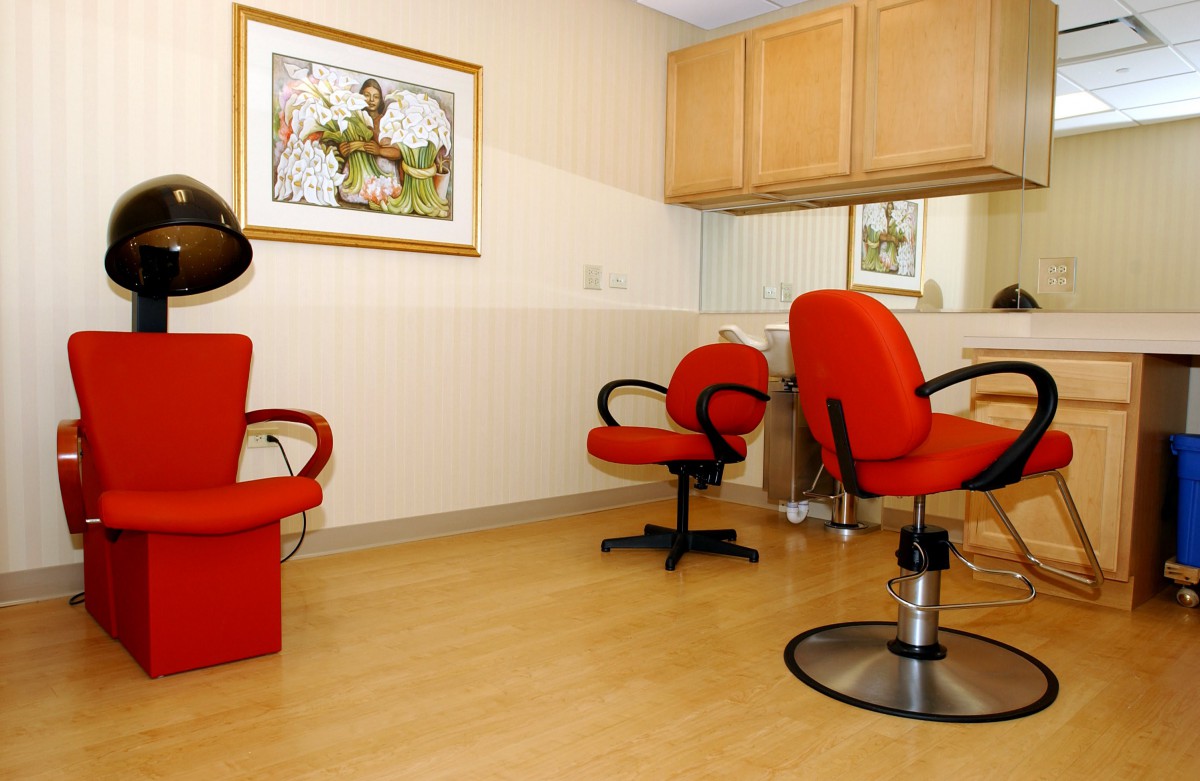 A cozy hair salon interior with vibrant red chairs and a wall mirror.