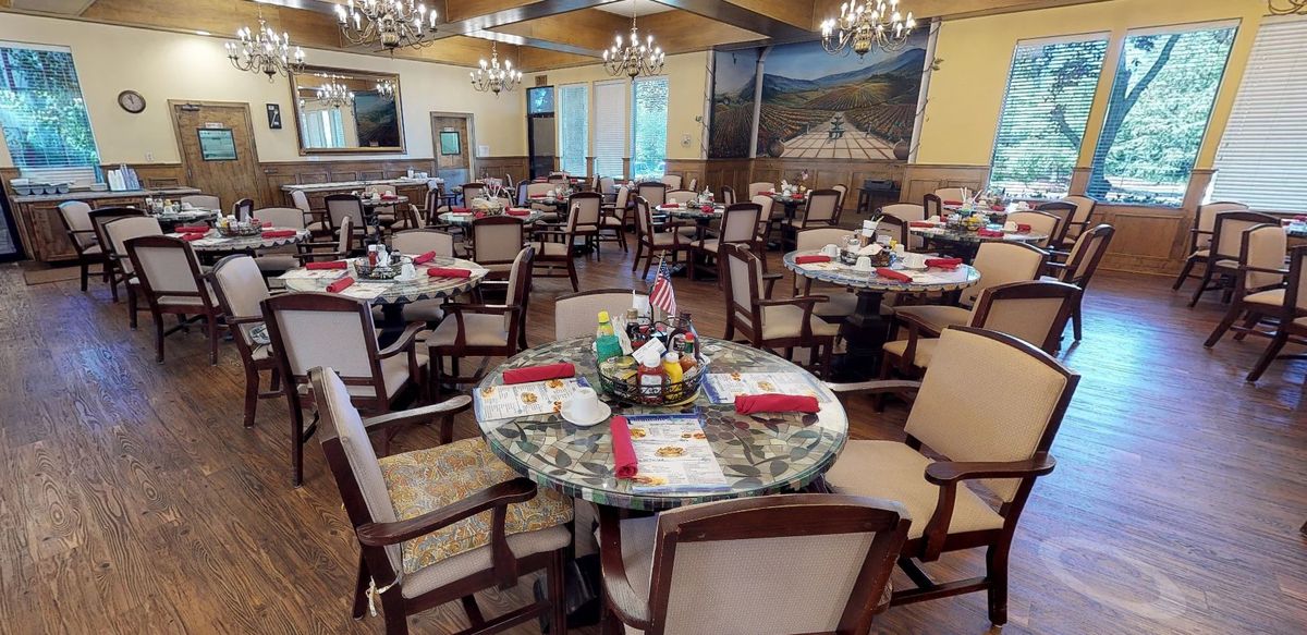 An elegant dining room with neatly arranged tables and chairs, adorned with chandeliers.