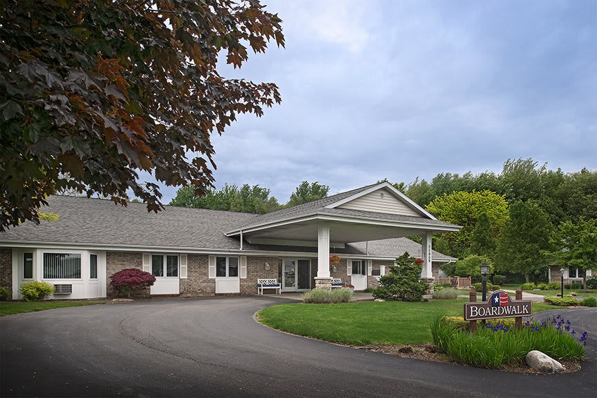 A spacious residential building with a circular driveway, surrounded by trees and a well-maintained lawn.