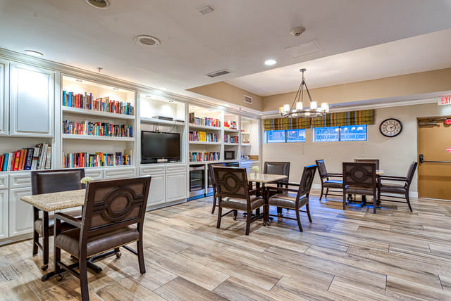 A cozy library room with bookshelves, tables, and comfortable chairs.