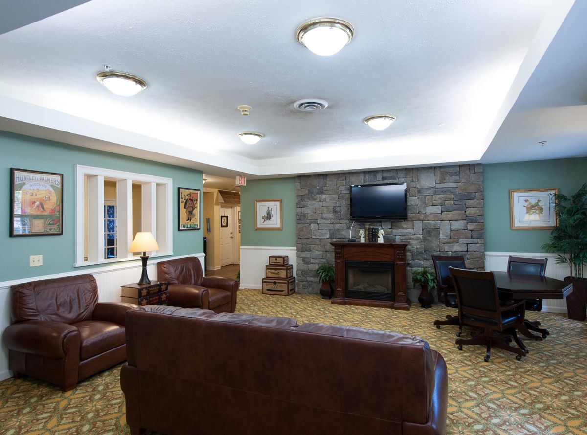 A cozy living room with brown leather sofas, a stone fireplace, and a wall-mounted television.