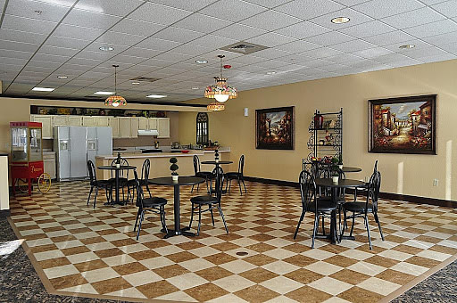 A small cafe interior with checkered flooring and several tables and chairs.