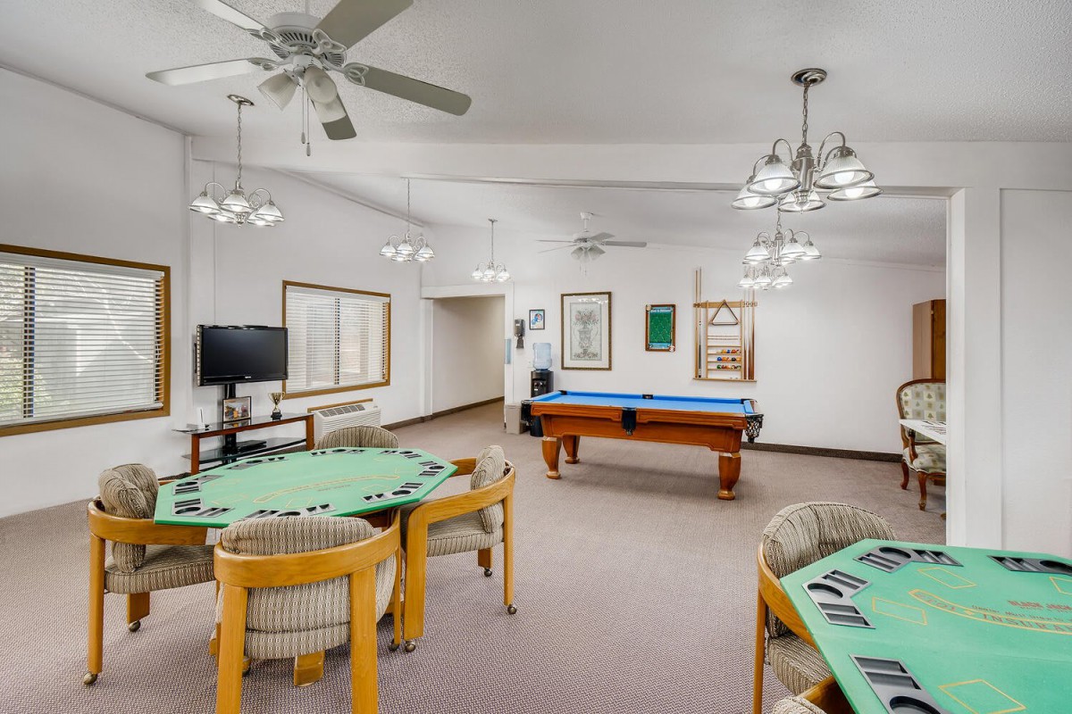 A spacious game room featuring a pool table, card tables, and comfortable seating.