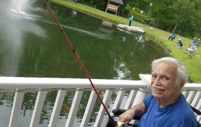 An elderly person enjoying a peaceful day fishing by the lake.
