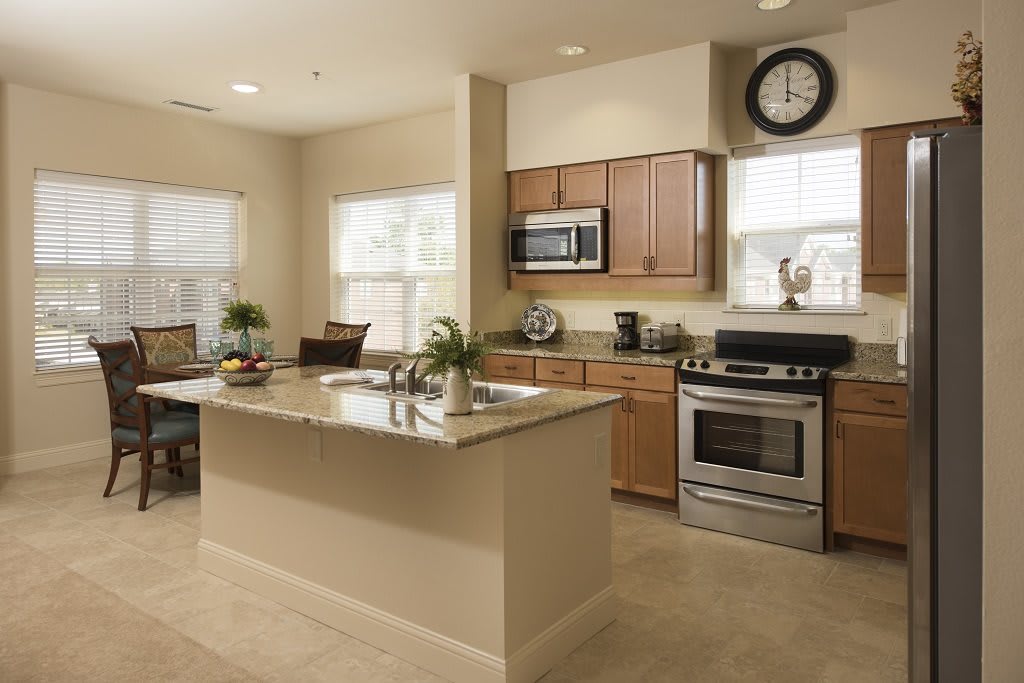 A modern kitchen with an island, stainless steel appliances, and a dining area.