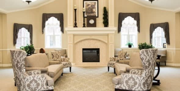 A cozy living room with a central fireplace, surrounded by comfortable seating and elegant decor.