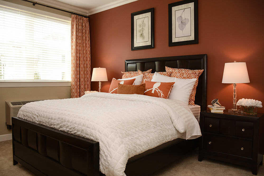 A cozy bedroom with a neatly made bed and warm color scheme.