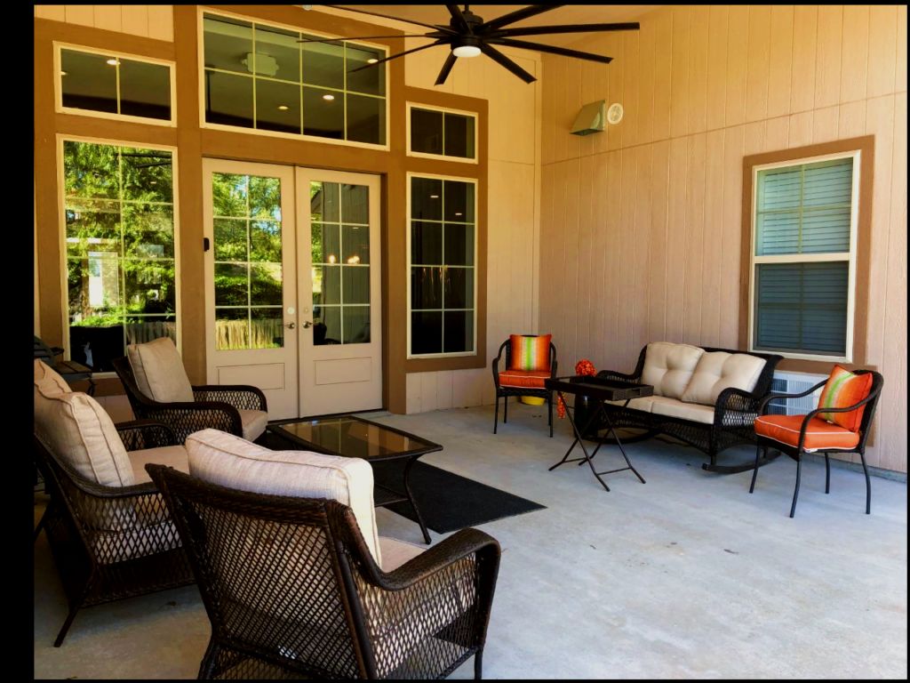 A cozy outdoor patio with comfortable seating and a ceiling fan.
