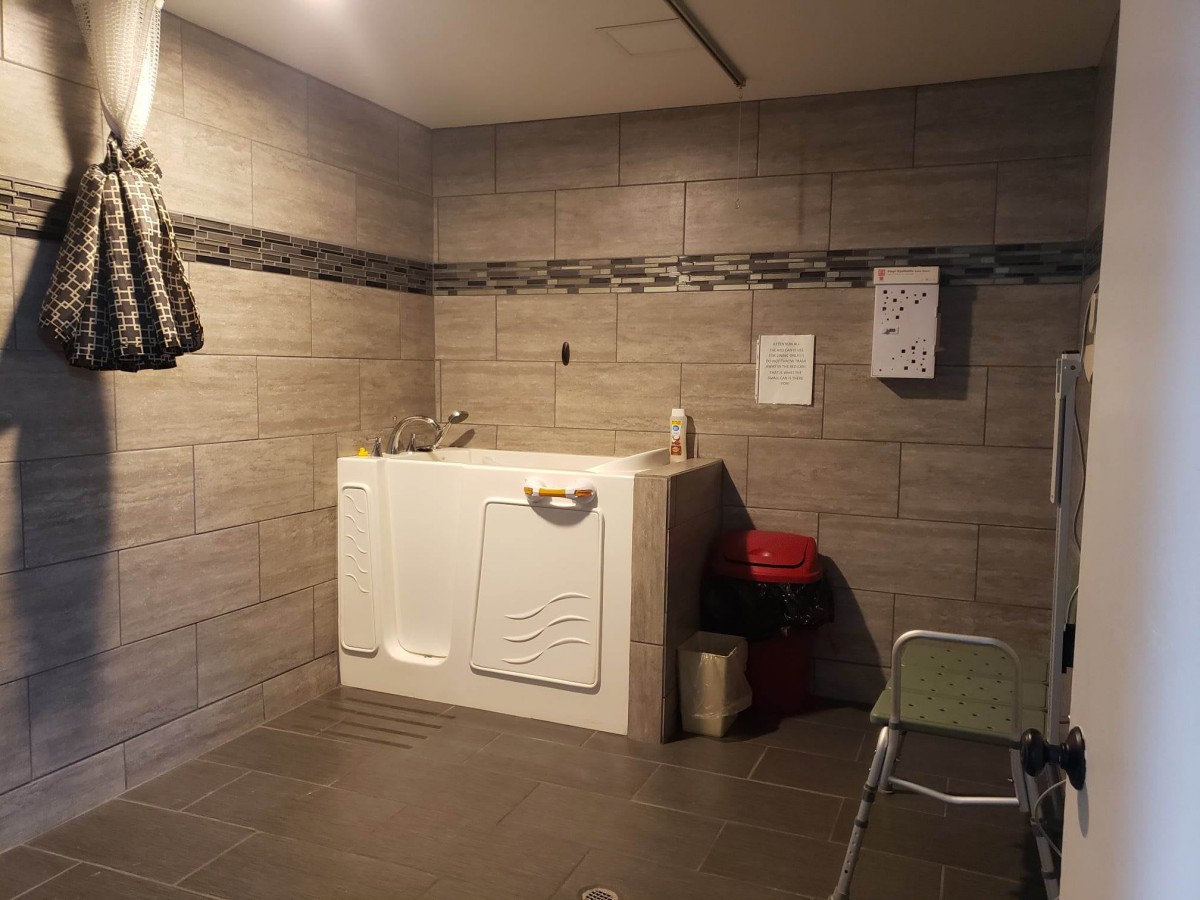 A bathroom designed for accessibility, featuring a walk-in bathtub and tiled walls.