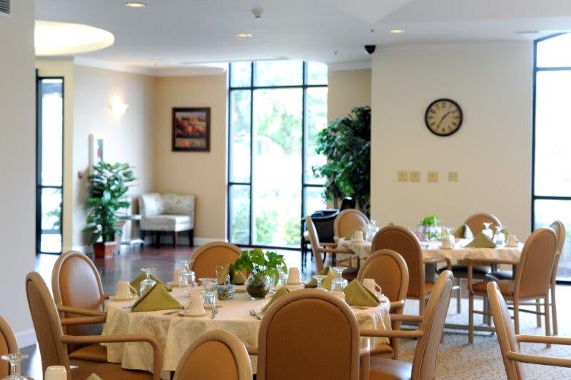 A modern and elegant dining room setup with neatly arranged tables and chairs, decorated with plants.