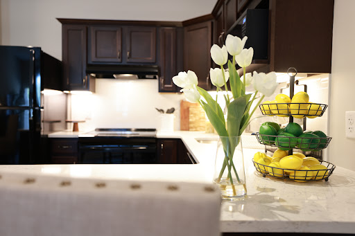 A modern kitchen featuring a stylish arrangement of white tulips and a colorful fruit basket.