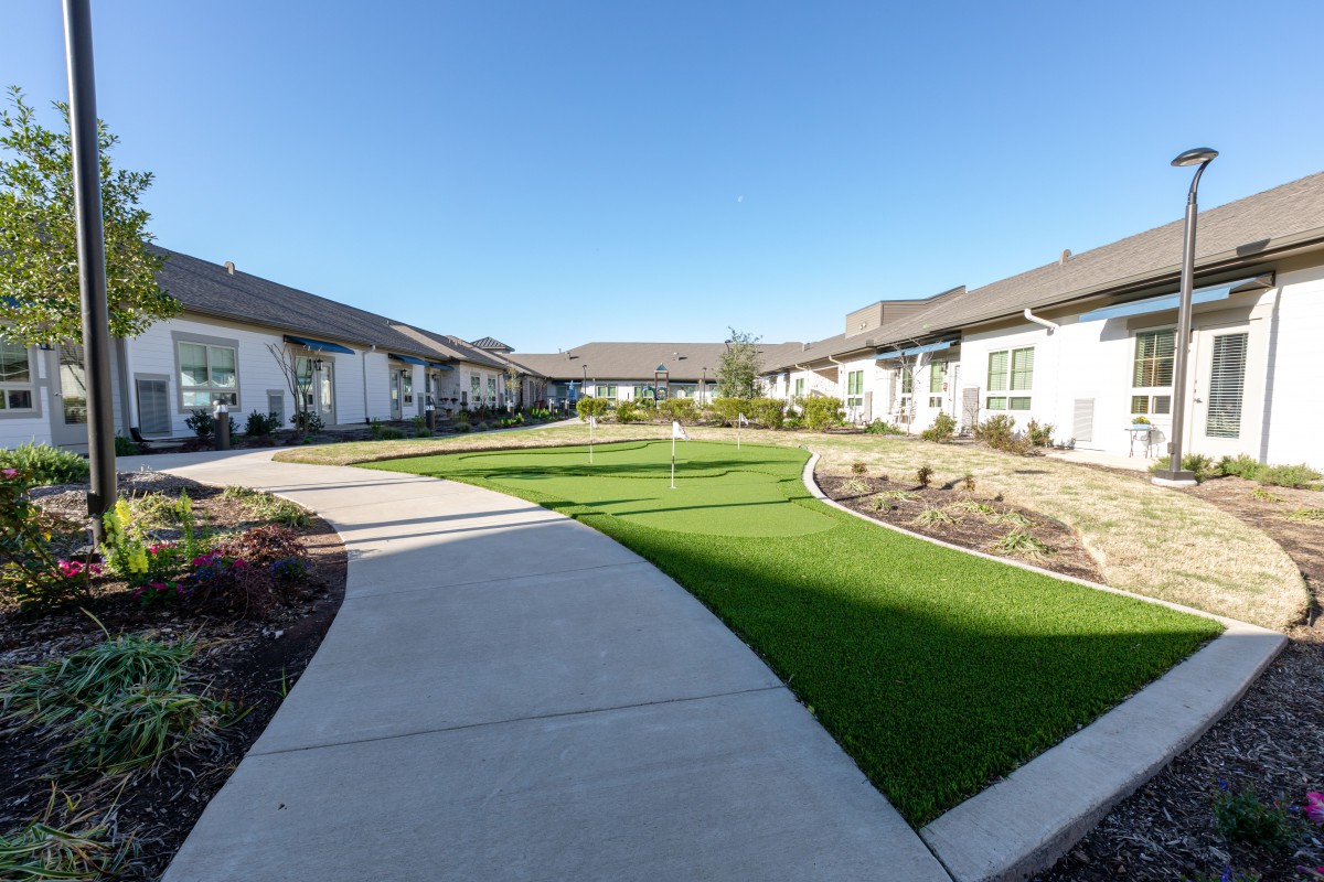 A well-maintained residential courtyard with a central grassy area surrounded by pathways and houses.