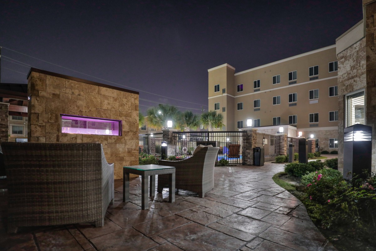 A nighttime view of a hotel patio area with outdoor seating and ambient lighting.