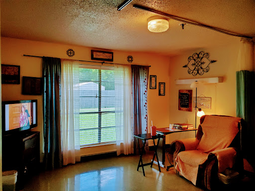 A cozy living room featuring a large window, soft curtains, and comfortable furnishings.