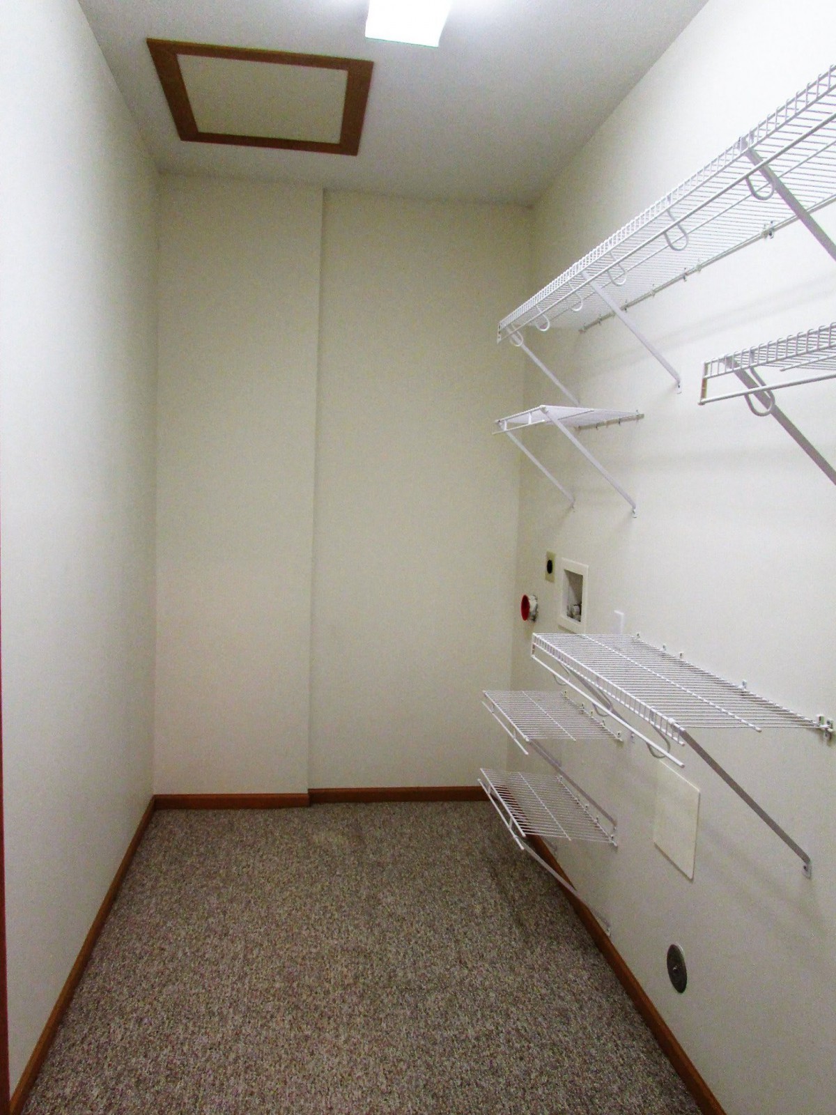 A small empty storage room with white shelves on the wall.